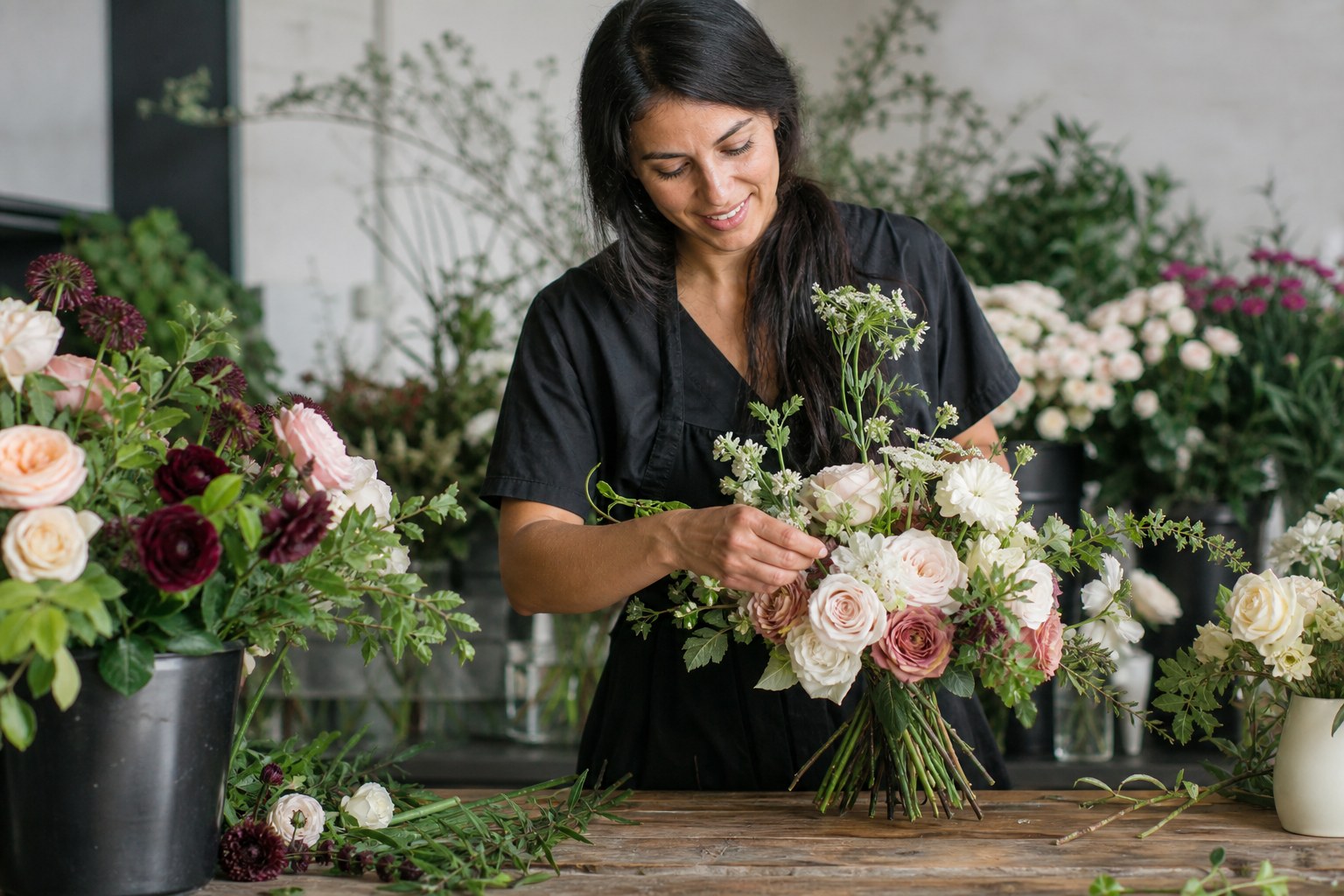 Wedding florist pricing wedding flowers while arranging a bridal bouquet in a studio