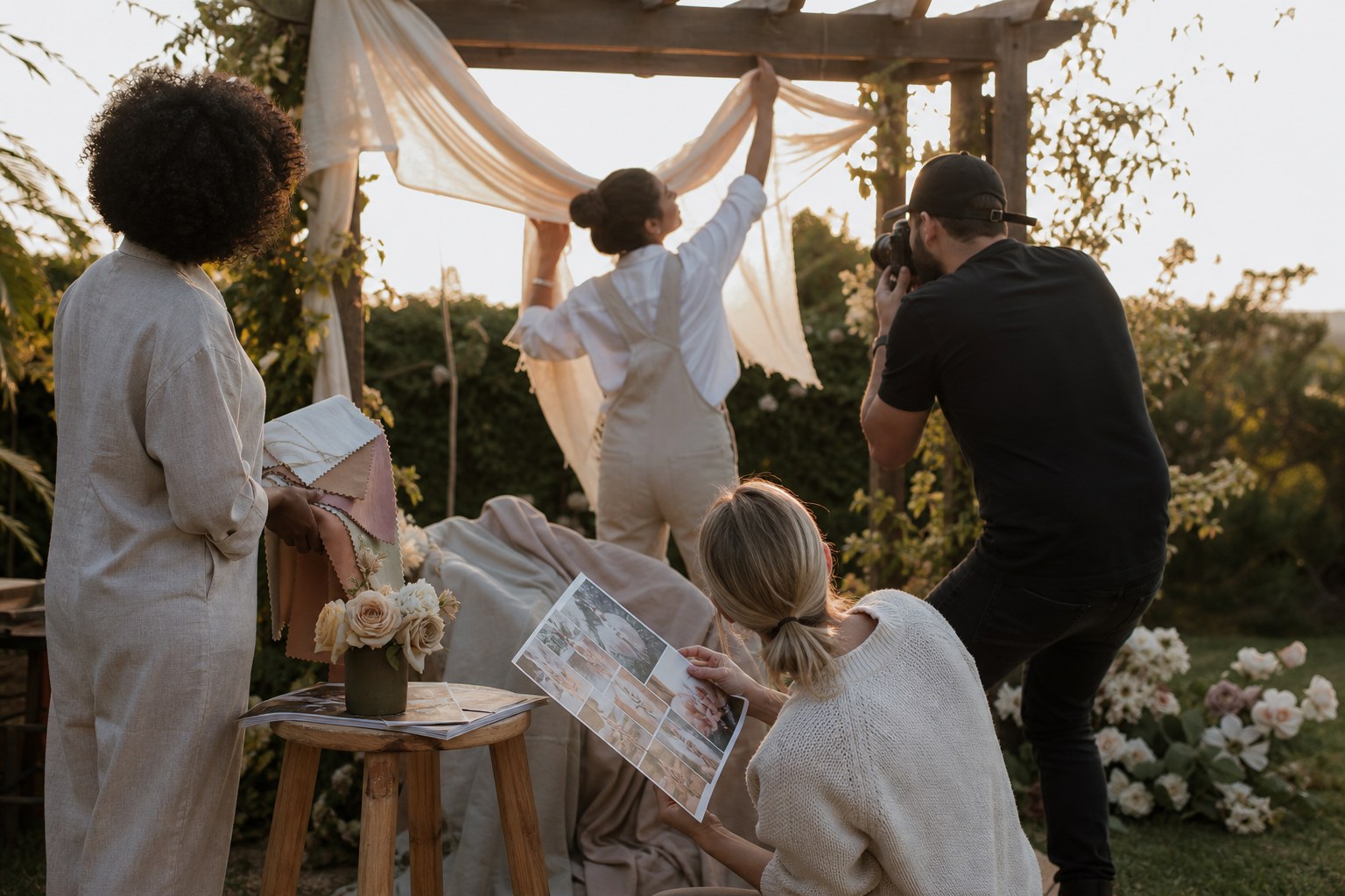 Wedding stylist styled shoot behind the scenes with a creative team draping fabric on a ceremony arbour